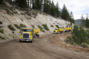 wesco transfer trailers pulled by yellow trucks on a winding dirt road